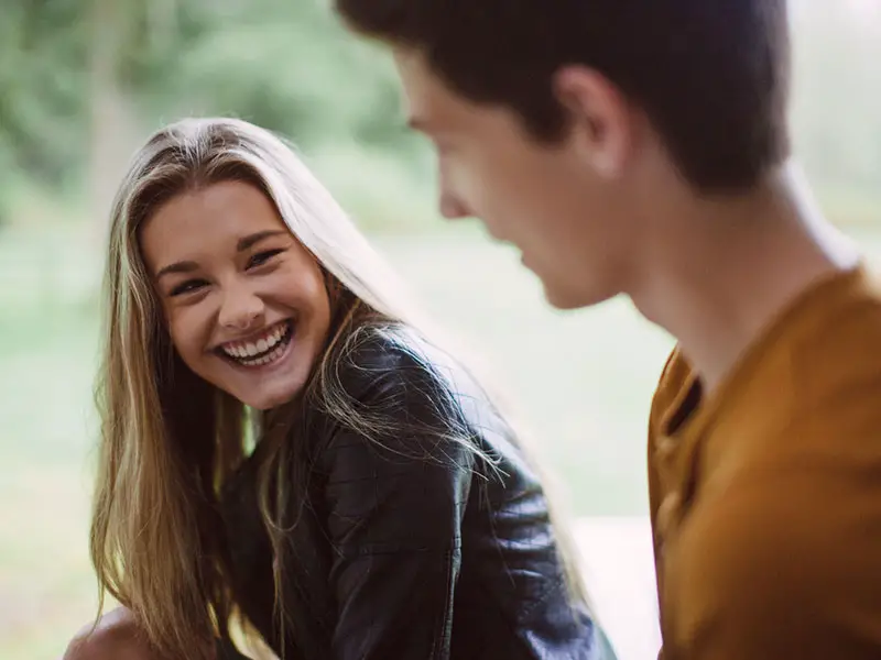 A girl is smiling while looking at a guy